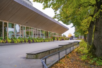 A modern building with large windows, surrounded by trees and falling leaves, Mainau Island, Lake