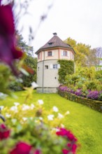 Tower-like building surrounded by flowering garden and green meadow, Mainau flower island, Lake