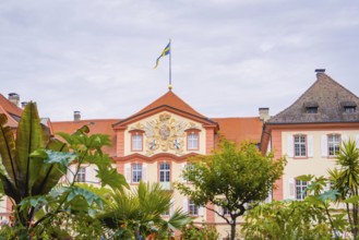 Historic building with a flag and plants in the garden, Mainau flower island, Lake Constance,