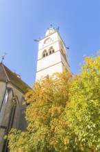 A high church tower surrounded by colourful autumn leaves and a clear blue sky, Überlingen, Lake