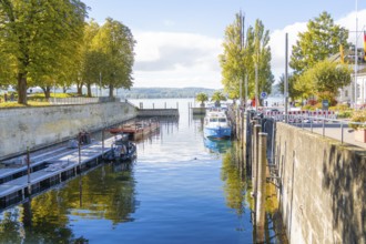 A small harbour with boats and autumnal trees on the shore, clear water, Überlingen, Lake