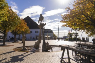 A sunny square with a fountain and autumnal trees, lined with buildings, Überlingen, Lake