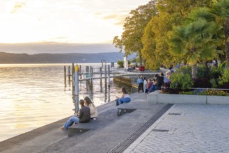People enjoying a quiet evening on the shore of a lake at dusk, Überlingen, Lake Constance, Germany