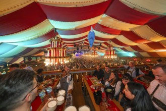 View from above of a colourfully decorated marquee with people celebrating, Cannstatter Wasen folk