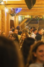 Cramped interior with lots of people, warm light and wooden furnishings, Cannstatter Wasen folk