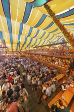 View of a lively festival tent with many people and colourful roof stripes, Cannstatter Wasen folk