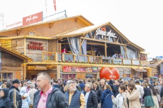 Large crowd in front of a Bavarian festival hall with a warm atmosphere, Cannstatter Wasen folk