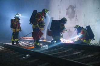 Firefighters during rescue operation on railway tracks at night, firefighting exercise in the new