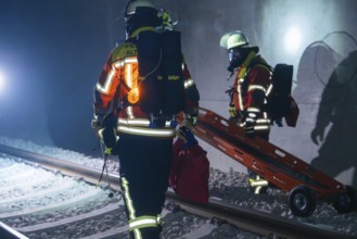 Firefighters carrying a stretcher on tracks in a tunnel, firefighting exercise in the new
