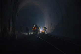 Firefighters at work in a dark tunnel on tracks, firefighting exercise in the new construction