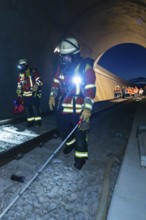 Firefighters with equipment walk along tracks in a tunnel, firefighting exercise in the new tunnel