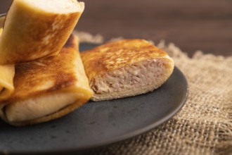 Fried crispy pancakes with meat and cheese on brown wooden background and linen textile. side view,