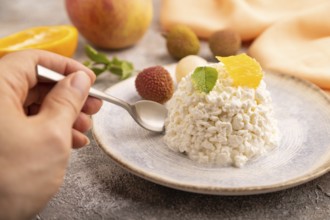 White ?ottage cheese, Curd, with orange and lychee with hand on brown concrete background and