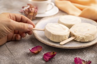 ?hocolate Ice cream in white glaze, cup of coffee, with hand on brown concrete background and