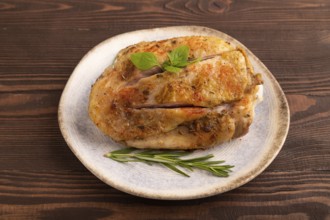 Fried Turkey Thigh with spices and rosemary on plate on brown wooden background. side view, close