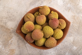 Ripe Lychee on clay bowl on brown concrete background, top view, flat lay, close up, minimalism