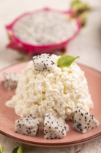 White ?ottage cheese, Curd, with Pithaya on gray concrete background and linen textile, side view,
