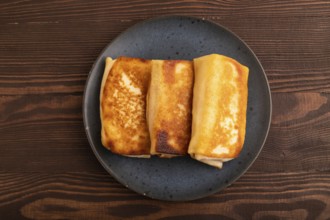 Fried crispy pancakes with meat and cheese on brown wooden background. top view, flat lay, copy