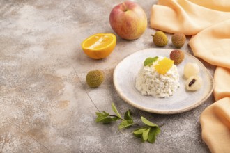White ?ottage cheese, Curd, with orange and lychee on brown concrete background and orange textile,