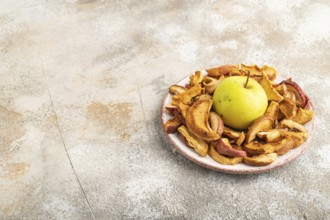 Dried Apples in ceramic bowl on brown concrete background. Side view, copy space, flat lay. healthy