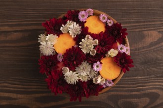 Wooden bowl with carrot slices and red Chrysanthemum flowers, Astrantia flowers, flower salad on