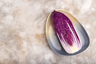Purple Chinese cabbage on blue plate on brown concrete background, top view, flat lay, copy space,