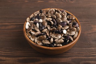 Wooden bowl with Kidney beans on brown wooden background, side view, close up, minimalism