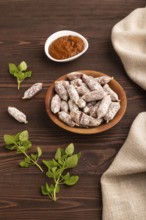 Small smoked Chicken sausages in wooden bowl on brown wooden background and linen textile. side