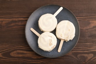 ?hocolate Ice cream in white glaze, on brown wooden background, top view, flat lay, close up