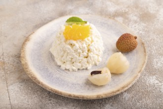 White ?ottage cheese, Curd, with orange and lychee on brown concrete background, side view, close