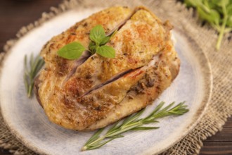 Fried Turkey Thigh with spices and rosemary on plate on brown wooden background and linen textile.