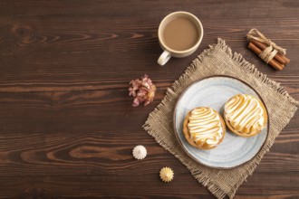 French lemon tart with meringue on brown wooden background, cup of coffee, linen textile, top view,