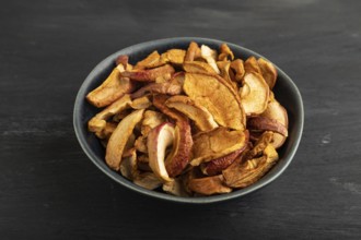 Dried Apples in ceramic bowl on black wooden background. Side view, close up. healthy food,