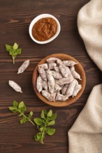 Small smoked Chicken sausages in wooden bowl on brown wooden background and linen textile. top