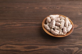 Small smoked Chicken sausages in wooden bowl on brown wooden background. side view, copy space