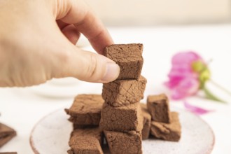 Chocolate marshmallow with cup of coffee with hand on white wooden background. side view, close up,