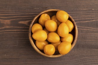 Pile of Smoked Quail eggs in bowl on a brown wooden background. top view, flat lay, close up