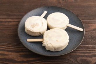 ?hocolate Ice cream in white glaze, on brown wooden background, side view, close up