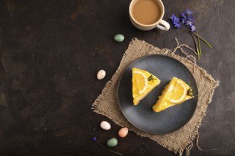 Lemon cake on black concrete background and linen textile, cup of coffee, top view, flat lay, copy