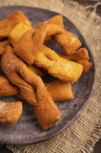 Crunchy biscuit Brushwood cookies sprinkled with powdered sugar on brown wooden background and