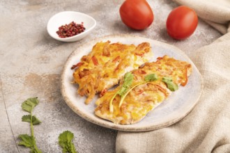 Baked chicken meat with cheese and tomatoes on brown concrete background and linen textile. side