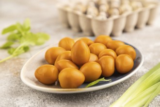 Pile of Smoked Quail eggs on plate on a brown concrete background. side view, close up, selective