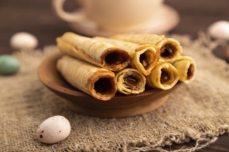 Waffles with caramel on brown wooden background and linen textile, cup of coffee, side view,