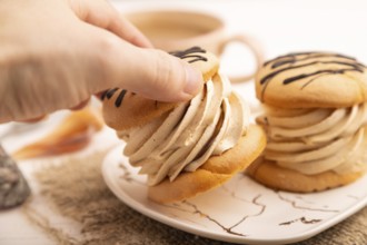 Caramel Cream Cakes with hand on white wooden background and linen textile, cup of coffee, side