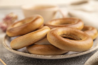 Homemade Ring Bagel with cup of coffee on brown concrete background and linen textile. side view,