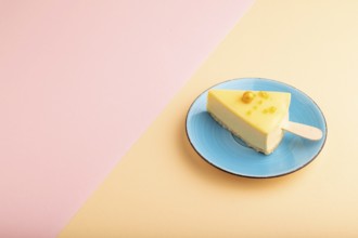 Yellow Cake pop with sprinkles on blue ceramic plate on pink and orange pastel paper background,