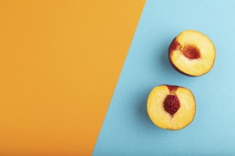 Peach Cut in half on orange and blue paper pastel background. Top view, flat lay, copy space.