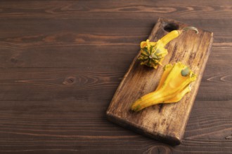 Decorative orange Pumpkin on cutting board on brown wooden background, side view, copy space,