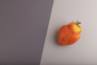 Red Heart Shape tomato on black and gray pastel paper background. Top view, flat lay, copy space.