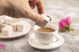 Coffee marshmallow with cup of coffee with hand on brown concrete background. side view, close up,